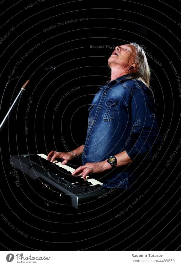 elderly man with long gray hair plays the keys instrument piano music long hair stage musical old musician art person keyboard senior melody male hand sound