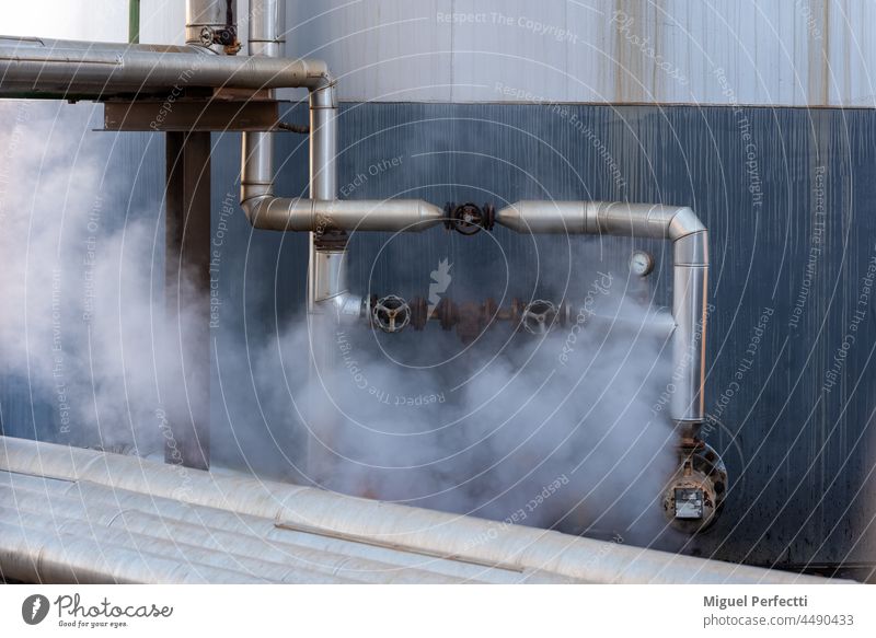Pipes protected by their high temperature giving off steam. pipe metal manufactures insulator tap valves faucet tank heat industry iron white smoke connections