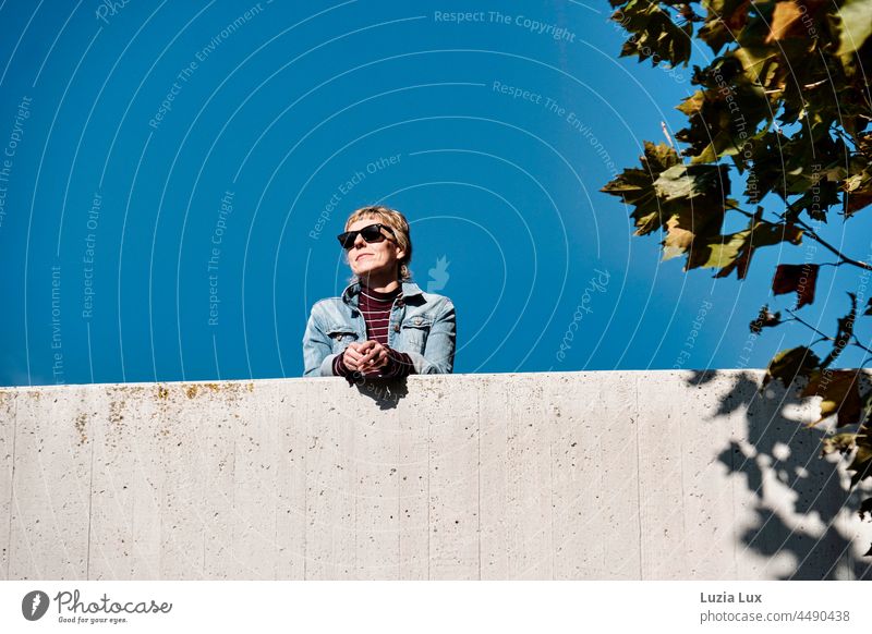 Blue hour, happy laughter: Woman with short hair and sunglasses standing on a bridge, looking at the sun cheerful Smiling smilingly amused Short-haired pretty