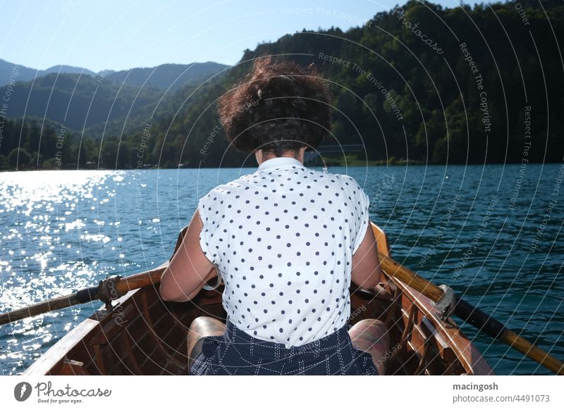 Rear view of young woman in rowing boat Rowing Rowboat Woman Exterior shot Lake Water Calm Vacation & Travel Nature Trip Summer Relaxation Boating trip