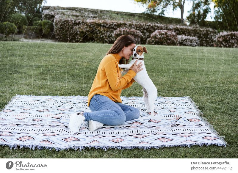 woman having fun with jack russell dog in park, sitting on blanket during autumn season. Woman cuddling dog. Pets and love concept happy kiss enjoy plaid lick