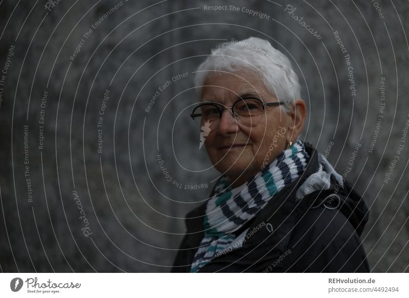 Senior woman in front of a concrete wall Senior citizen Grandmother Woman age 60 years and older portrait Face Retirement Pensioner Old Human being