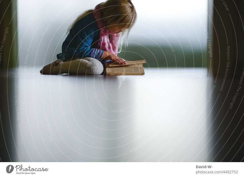 Child sitting on the floor and leafing through a book eager for knowledge Reading Book To leaf (through a book) inquisitive youthful highly gifted Study Know
