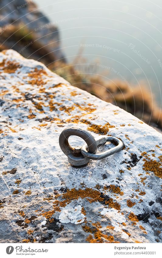 Сlimbing carabiner hook and trigger device in stone. Carabiner for mountaineering on rocky and seascape background . Extreme sport concept. climbing carbine