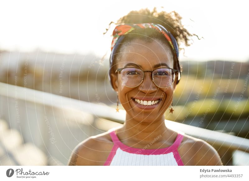 Portrait of young woman smiling outdoors at sunset millennials eyeglasses curly joy outside colorful afro confident female beauty vacation travel satisfied