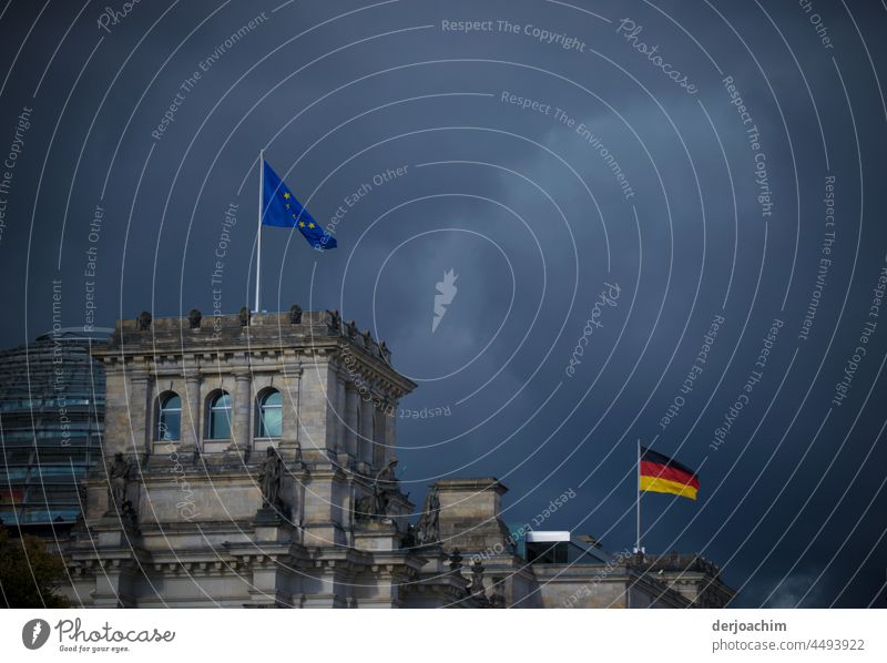 Ganz dunkle Wolken über dem Regierungsviertel. Zwei Fahnen , die Europa und die Deutsche wehen im stürmischen Wind über dem Bundestag. regierungsviertel