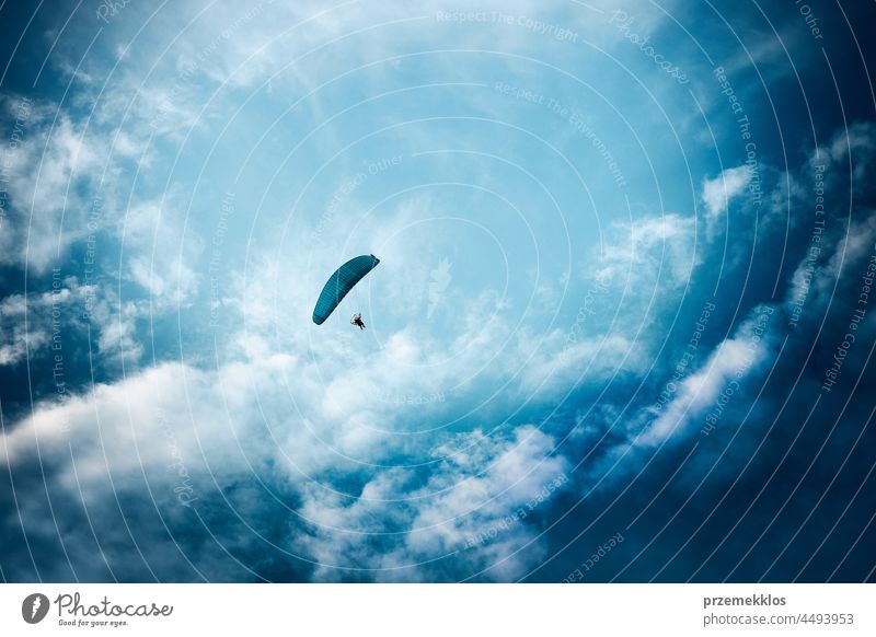 Paraglider flying in the cloudy sky paraglider sport flight air freedom hobby recreation person extreme action alone brave wind high skydiving adrenaline fun