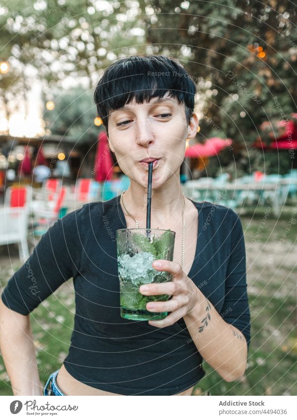 Woman drinking cocktail with mint in garden woman summer park refreshment beverage enjoy glass female cool tasty cheerful delicious cube happy ice alcohol cold