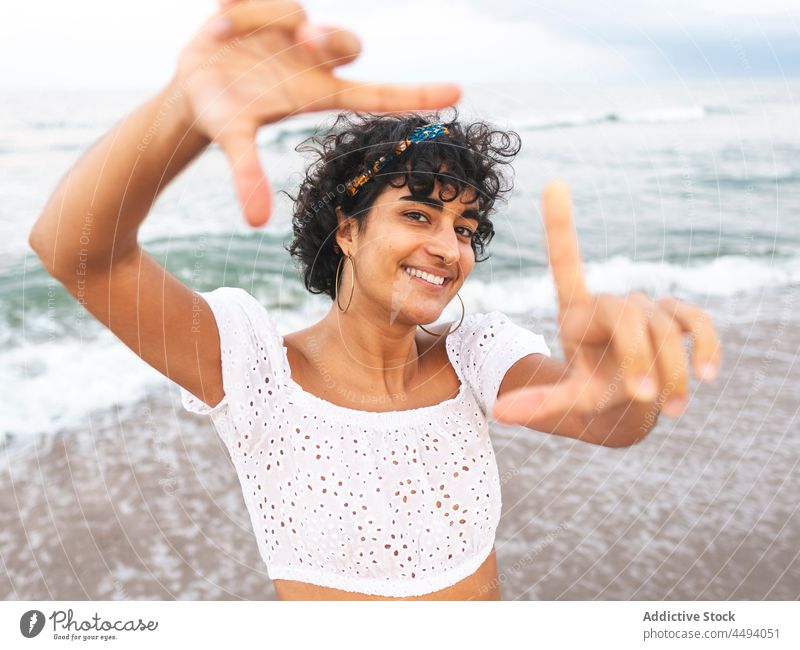Ethnic woman showing framing gesture on seashore frame sign photo summer smile beach cheerful female ethnic carefree happy seaside charming coast delight joy