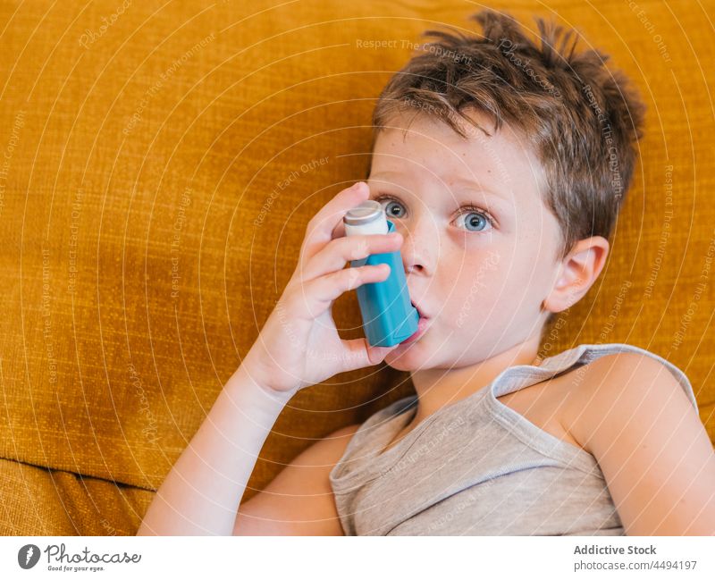Ill child using inhaler at home asthma ill boy care breath treat problem kid little sick medicine health care medical oxygen childhood breathe cure illness sofa