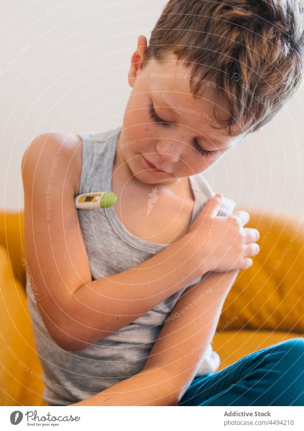 Sick child measuring temperature at home measure cold flu ill electronic thermometer sick boy kid fever infection illness couch symptom virus unwell sofa