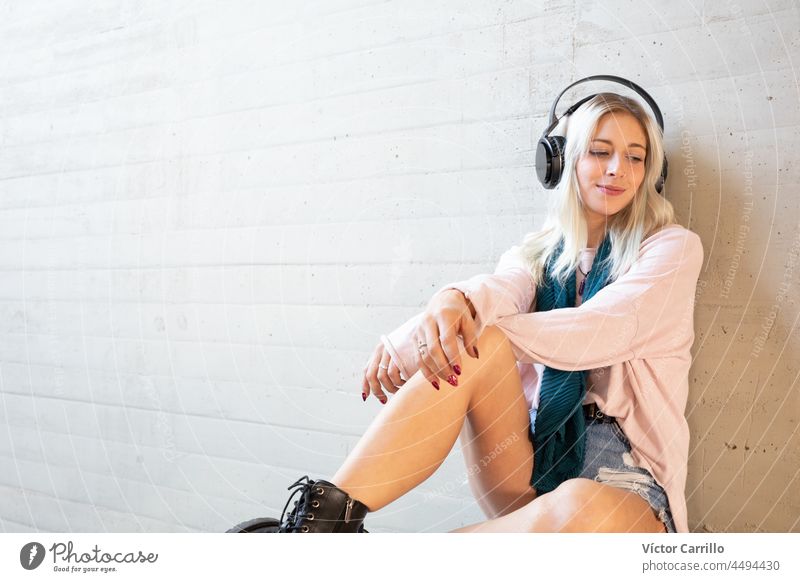 a young blonde woman chilling and enjoying music with headphones earphones person dance listen listening model relaxation smile student stylish trendy pretty