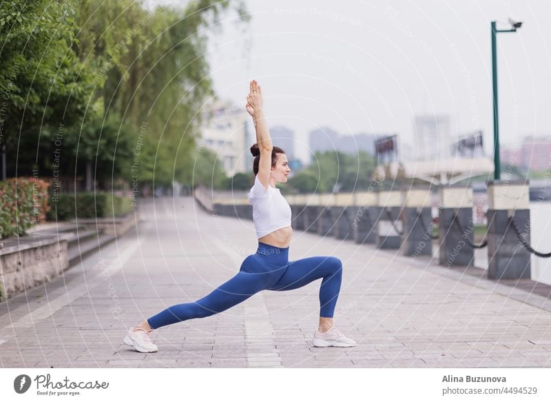 Portrait of happy young caucasian woman exercising yoga outdoors early morning. Beautiful girl practicing asana in park at summer exercise healthy wellbeing