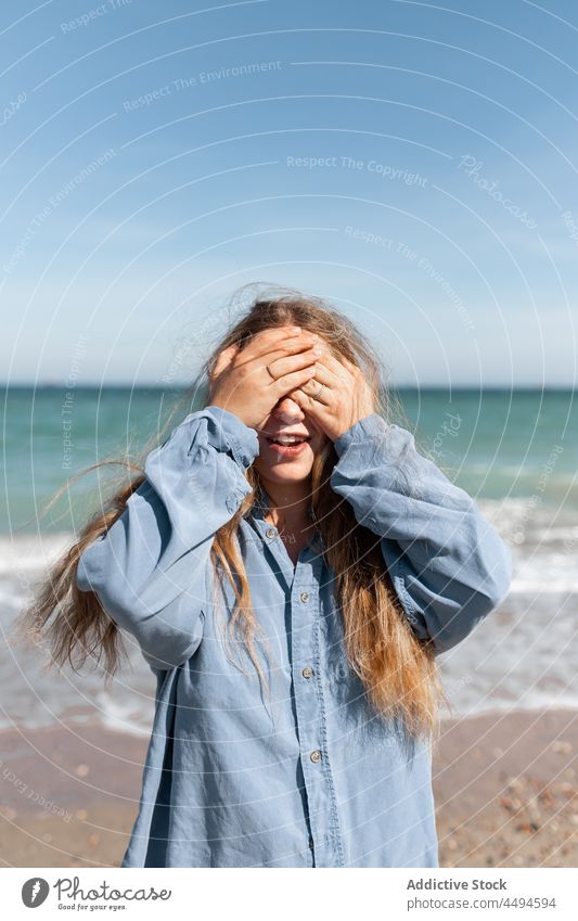 Woman covering face with hands woman summer sunlight coastline seashore trendy daytime wind hide peaceful appearance contemporary female gesture finger style