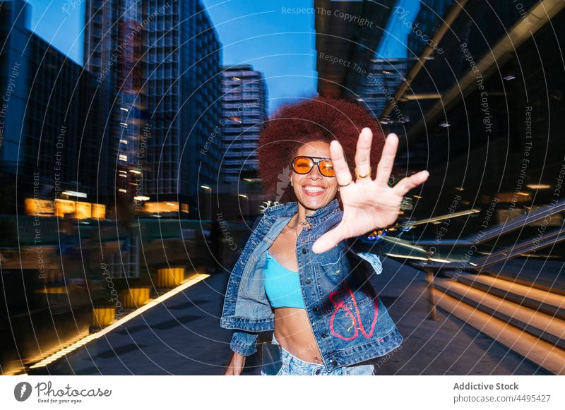 Stylish woman with Afro hairstyle running to camera street afro fashion apparel evening reach out building hand outfit dark twilight house appearance female