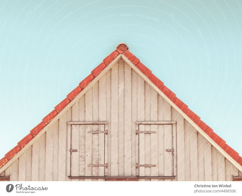 House gable with wooden facade and two closed doors in front of pale blue sky pediment house gables Gable Wooden facade locked too Hinges Facade