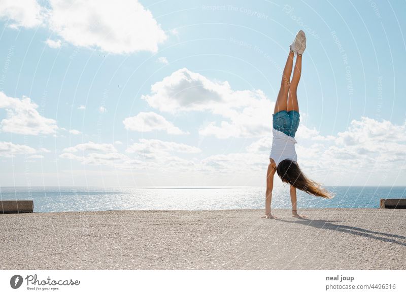 Young girl doing handstand on the edge of a concrete platform by the sea Freedom youthful Girl Young woman Brave Perspective Looking Far-off places Horizon