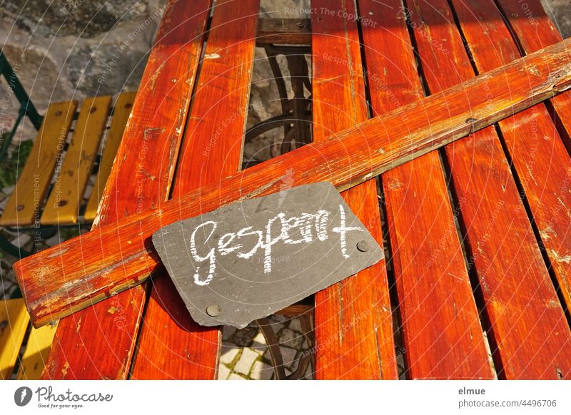 On the red painted wooden beer garden table lies a removed wooden slat across and a slate board with the inscription - locked -. beer table beer table set