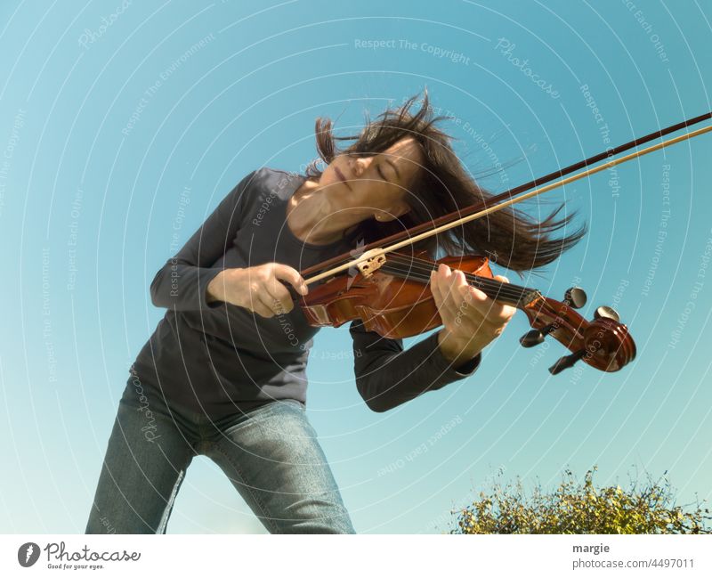A woman plays the violin under a blue sky Woman Sky Human being Feminine Colour photo Young woman portrait Violin Playing Adults Music Musical instrument Joy