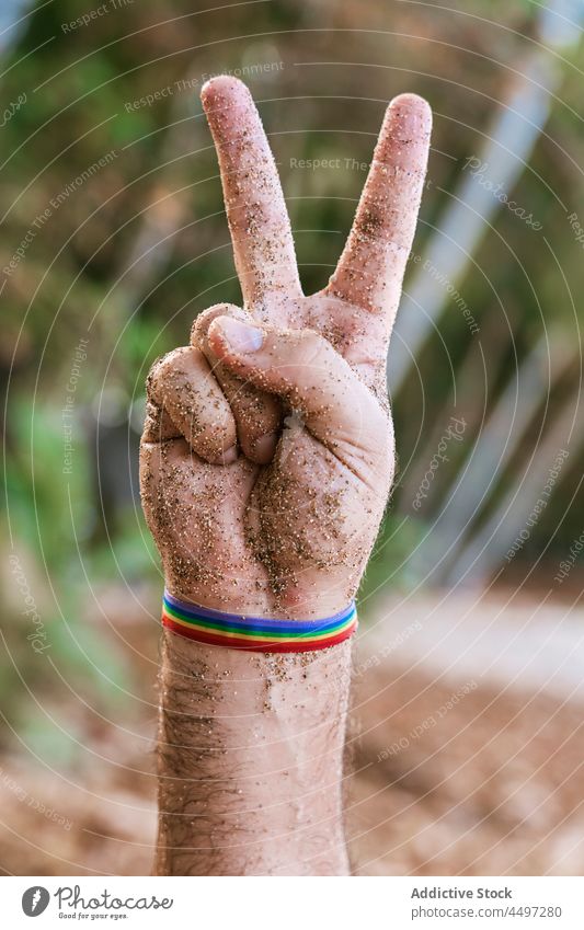 Man with rainbow ribbon on hand showing peace gesture man bracelet symbol lgbtq tolerance male São Tomé and Príncipe africa homosexual demonstrate plant sign