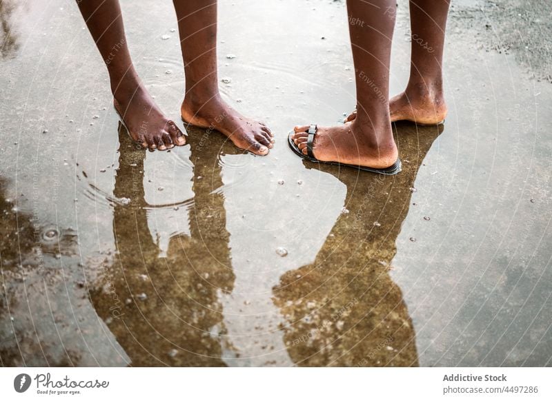 Black barefoot people standing in puddle on street wet asphalt road water sidewalk flip flop São Tomé and Príncipe africa african black reflection daylight