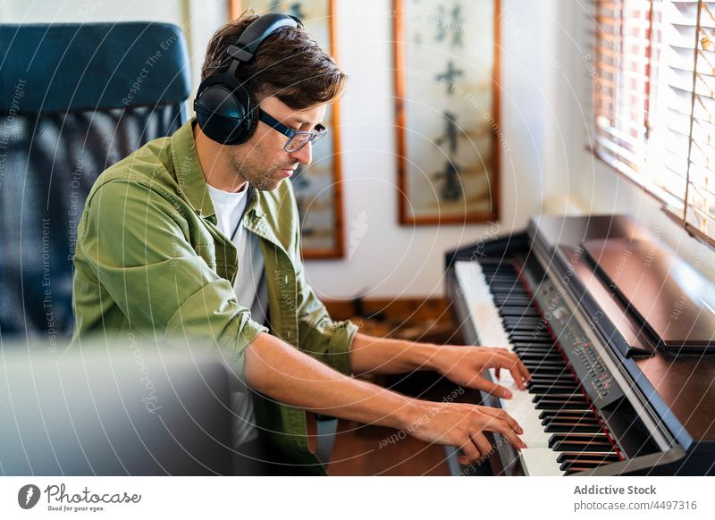 Male musician playing on piano in light room man pianist headphones compose instrument melody practice talent male window sit casual hobby keyboard skill