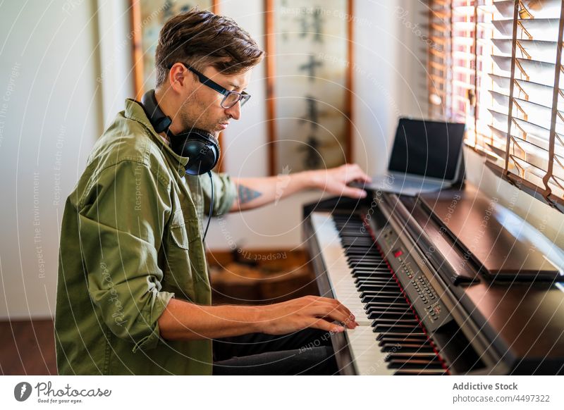 Male musician playing on piano in light room man pianist headphones compose instrument melody practice talent male window sit casual hobby keyboard skill
