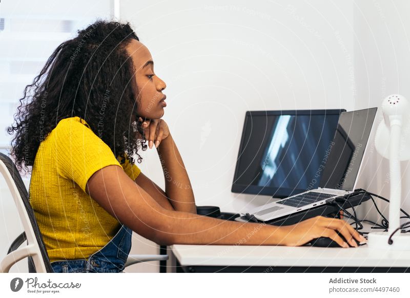 Black woman using laptop at home typing gadget content keyboard brunette table curly hair ethnic african american work freelance student female casual sit child