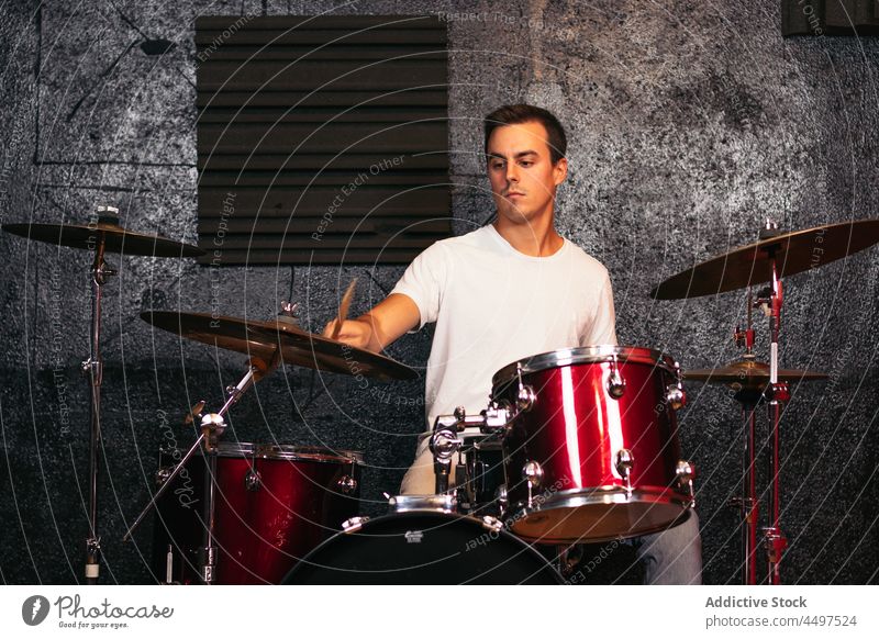 Male drummer playing in light studio man instrument crash perform club musician skill talent professional male young pensive gray live melody audio thoughtful