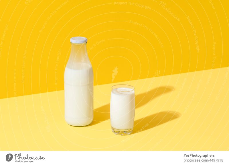 Milk in glass and bottle, minimalist on yellow background abstract beverage bio breakfast bright calcium clean color container copy space cow cream creative