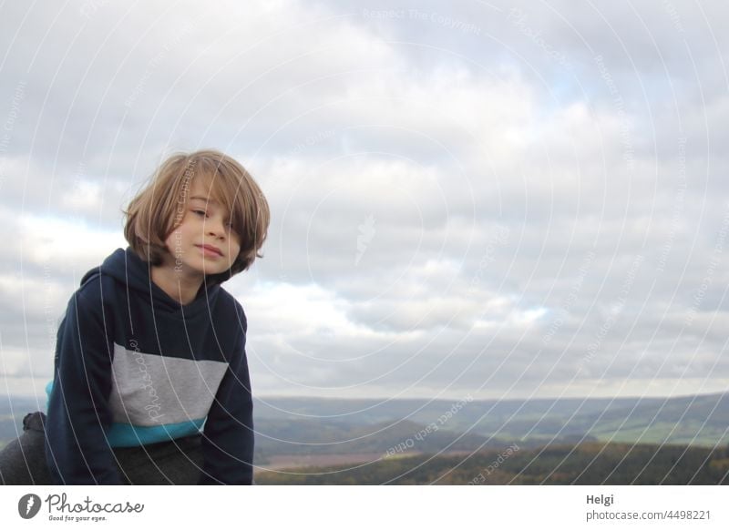 Boy sitting in nature against cloudy sky, mountains of Rhön in background Child Human being Boy (child) out Nature Sit look portrait Upper body Sky Clouds Trip