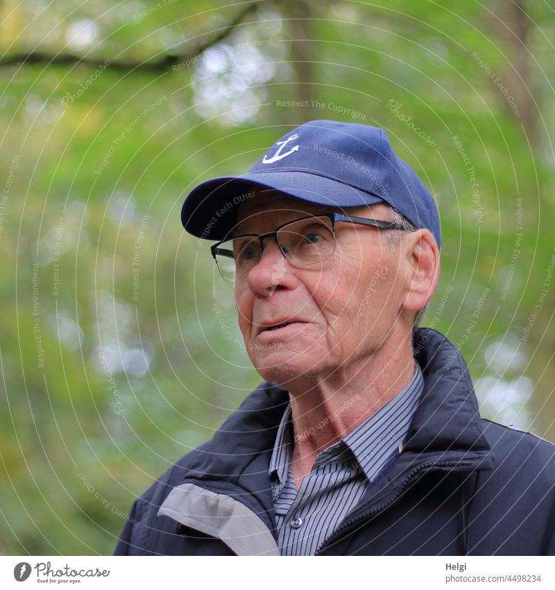 Portrait of senior citizen with cap, glasses and jacket in front of natural blurred background Human being Man Senior citizen portrait out Nature Eyeglasses