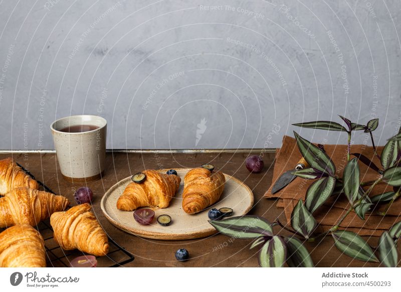 Delicious croissants placed near cup of tea on wooden table dessert breakfast morning yummy tasty baked fruit food plate sweet fresh pastry delicious serve