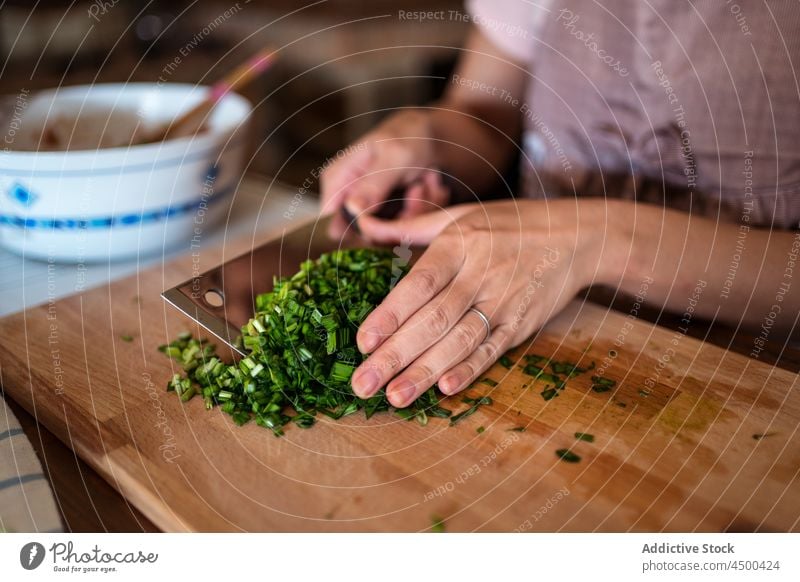 Woman chopping green onion on wooden board in kitchen woman herb cutting board cook fresh meal ingredient food healthy prepare female apron housewife