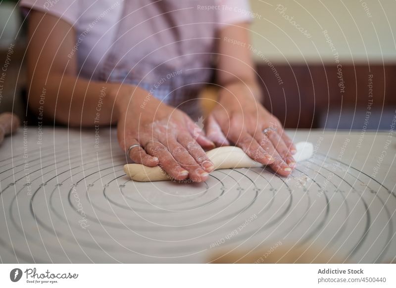 Crop housewife rolling dough with hands woman cook kitchen cuisine dumpling homemade prepare food process recipe culinary female casual apron meal knead table