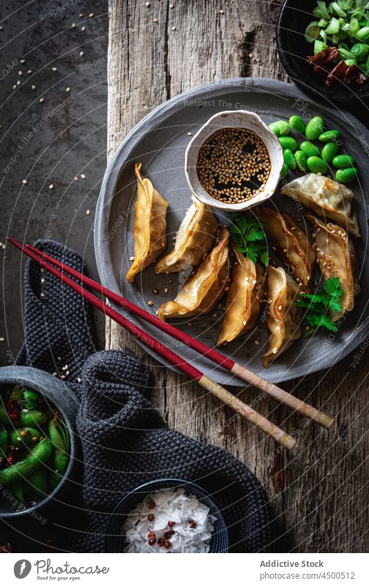 Gyozas with beans and sauce near spices and pea pods gyoza soy sauce bowl chopstick meal food lunch seed sesame natural tradition nutrition asian food dinner