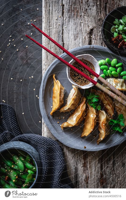 Gyozas with beans and sauce near spices and pea pods gyoza soy sauce bowl chopstick meal food lunch seed sesame natural tradition nutrition asian food dinner