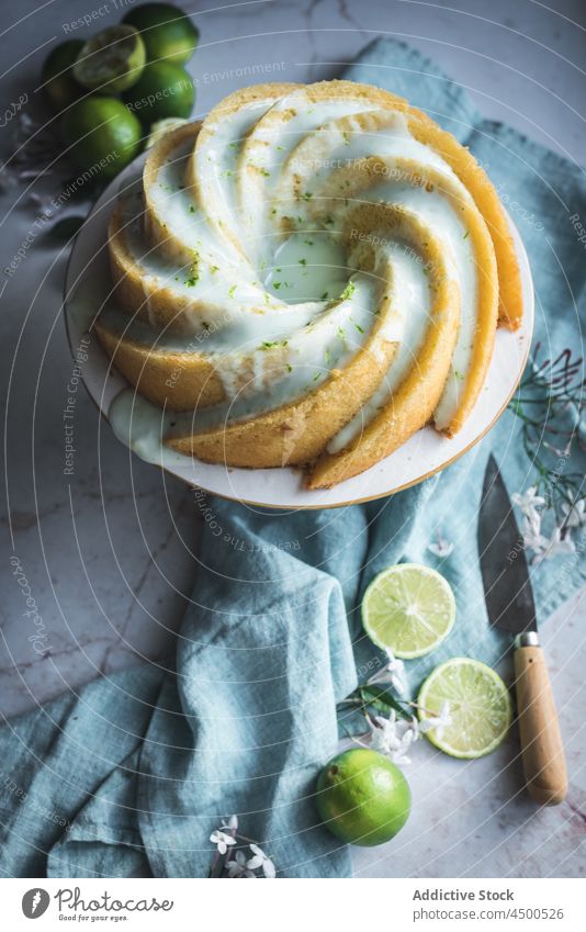 Lime sponge cake on plate near flowers and lime slices dessert confectionery citrus biscuit baked tasty fruit appetizing palatable culinary bakery composition
