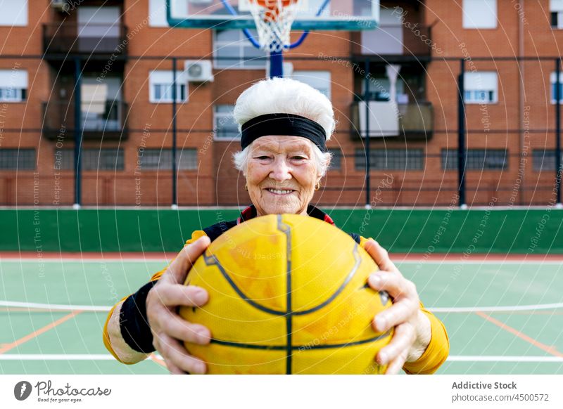 Cheerful senior woman with basketball on playground game sports ground hobby healthy lifestyle training mature smile cheerful positive female activity