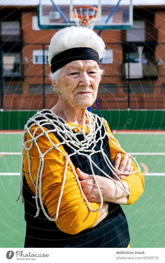 Senior woman with net on sports ground senior basketball game healthy lifestyle hobby pastime training having fun mature female activity activewear hoop