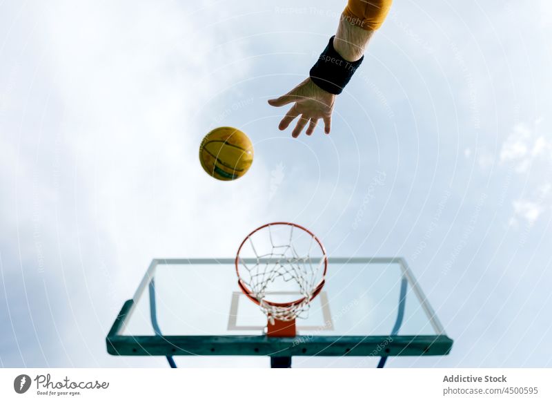 Unrecognizable sportsman throwing ball into hoop basketball sports ground game motion score net equipment court backboard play shape professional summer hobby