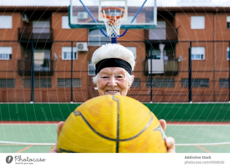 Cheerful senior woman with basketball on playground game sports ground hobby healthy lifestyle training mature smile cheerful positive female activity