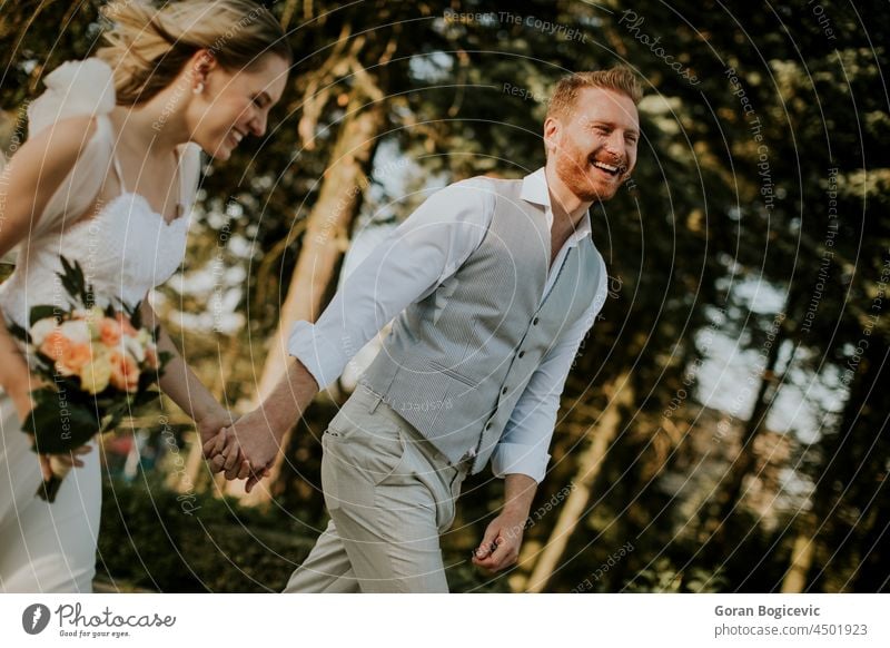 Young newlywed couple walking in the park beautiful beauty bride caucasian cheerful contact day dress embrace emotion family feelings female ginger groom