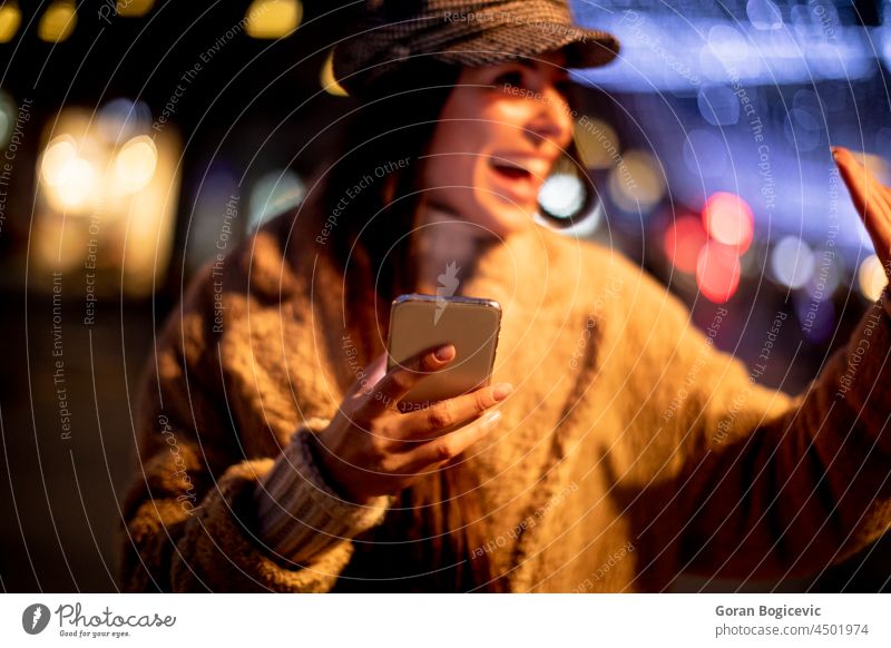 Pretty young woman using her mobile phone in the street at Christmas time bag beautiful browsing cap cellphone christmas city cityscape communication concept