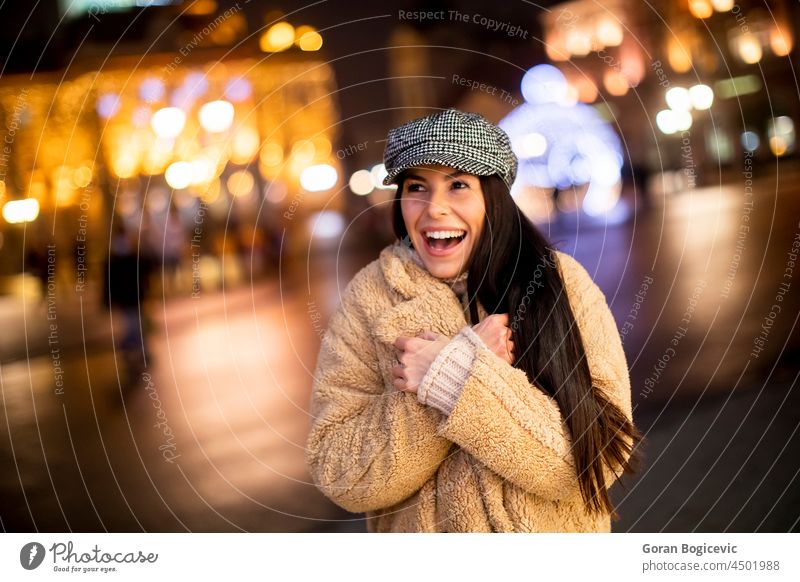 Pretty young woman on the street at cold Christmas night arms beautiful cap christmas city cityscape clothes concept crossed decoration evening female freeze
