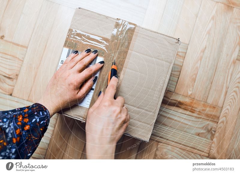 Woman opening parcel online order. Unpacking box with ordered items preparing shipment cardboard shipping delivery above close floor gift home package packaging