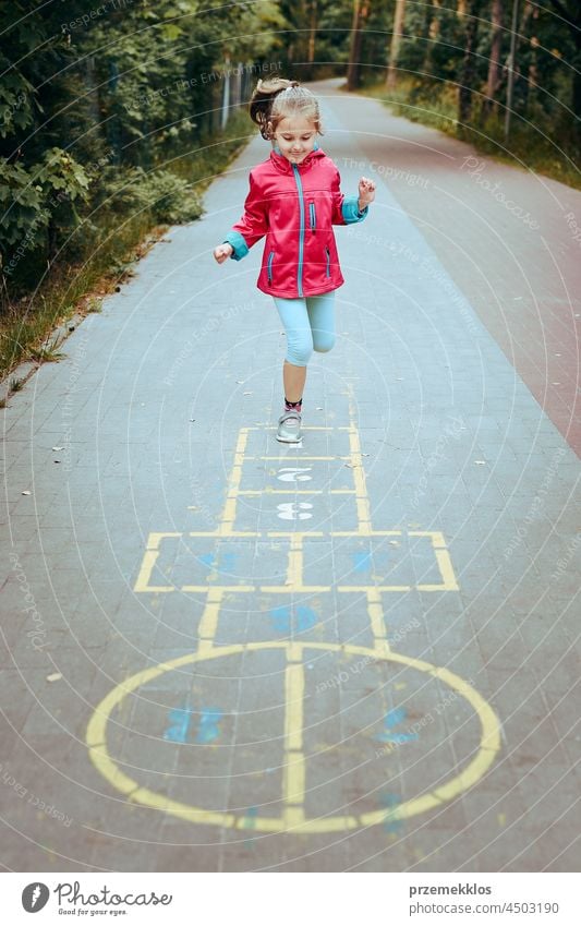 Active little girl playing hopscotch on playground outdoors jumping preschool game child fun chalk outside exercise joy kid active happy sidewalk enjoyment