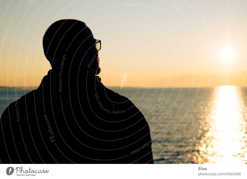 Back view of a man looking at the sun over the sea Man Sun Ocean Sunrise Horizon Rear view Silhouette Water Sky Surface of water Sunlight Far-off places