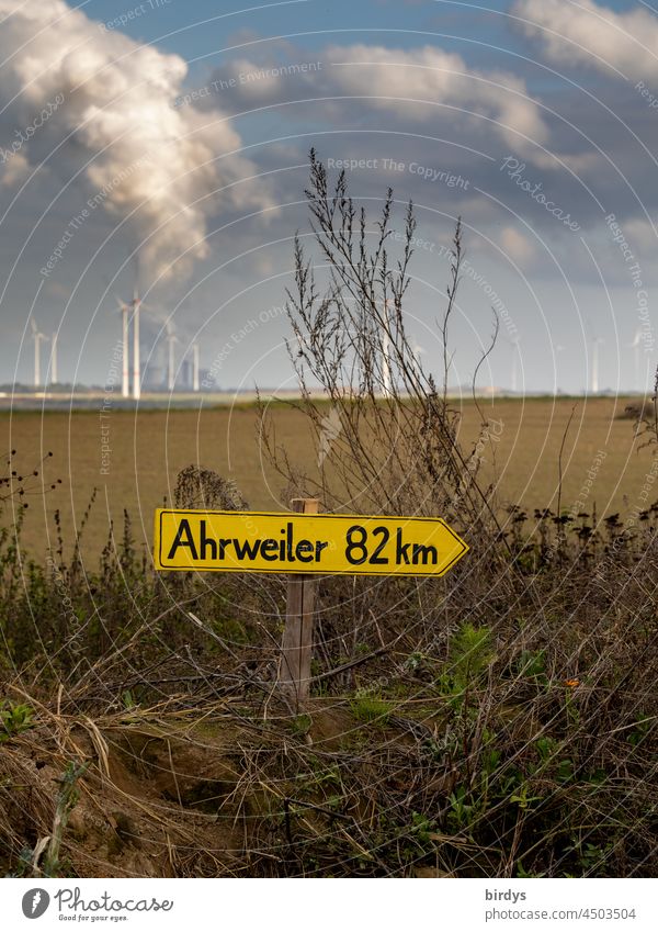 At the Garzweiler 2 opencast lignite mine, a sign pointing the way to the Ahrweiler flood disaster area. In the background the opencast mine and a lignite-fired power plant whose CO2 emissions are partly responsible for climate change.