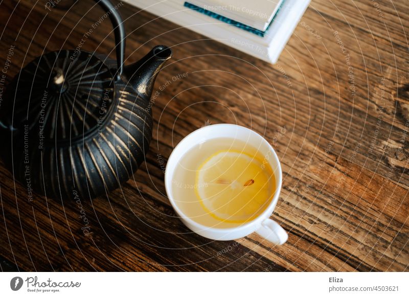 teacup with tea and lemon slice next to a teapot on wooden table Tea cup Teapot Slice of lemon Hot drink Cup Table Wooden table coffee table Lemon lemon tea